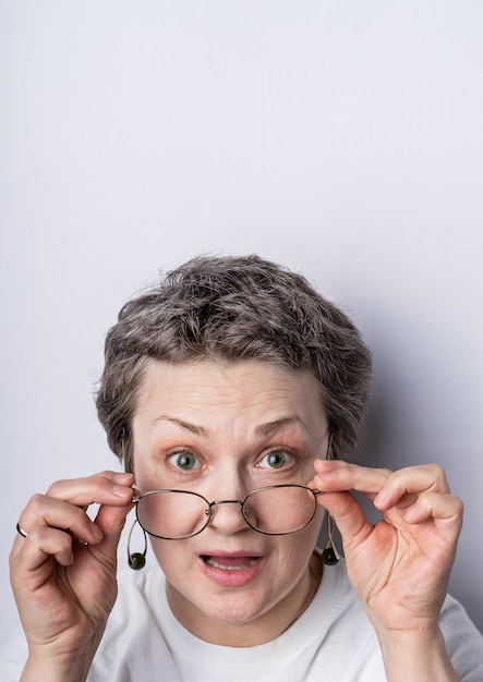 Foto de una mujer de cabello gris con gafas con expresión juguetona en su rostro