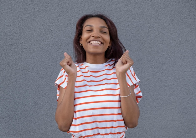 La foto de una mujer carismática y encantadora con el pelo rizado tiene una divertida sonrisa con dientes en la cara satisfecha después de un trato exitoso mira a la cámara y viste poses de ropa casual blanca en el estudio Emociones felices