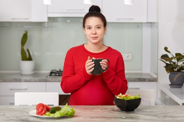 Foto de mujer embarazada bebe bebidas calientes durante la cena