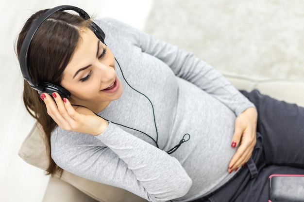 Foto foto de mujer embarazada positiva escuchando música