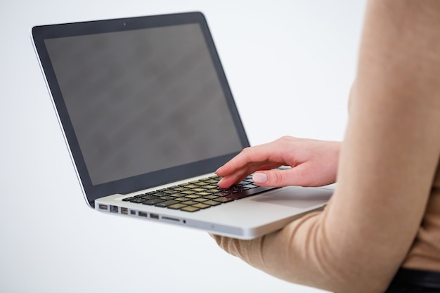 Foto de una mujer encantadora sosteniendo un portátil y escribiendo en negocios