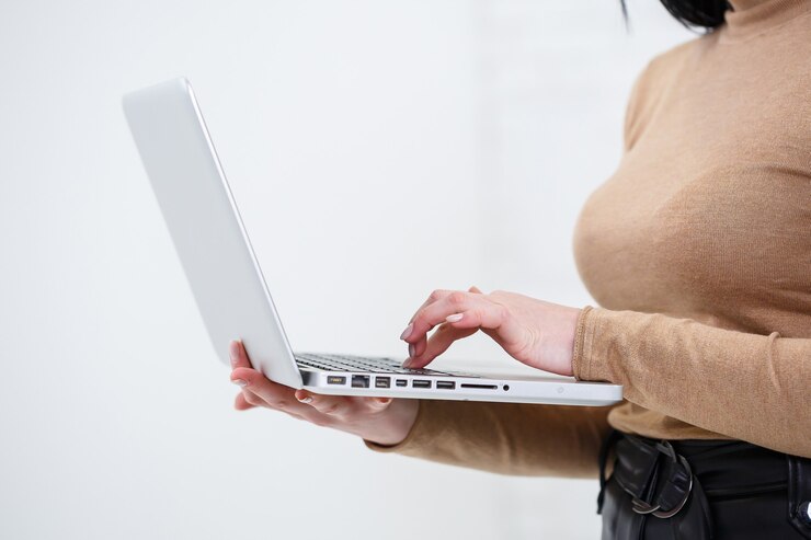 Foto foto de una mujer encantadora sosteniendo un portátil y escribiendo en negocios