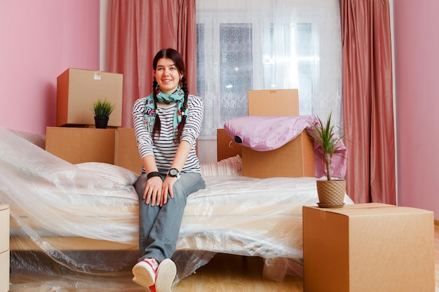 Foto de mujer feliz sentada en un sofá entre cajas de cartón