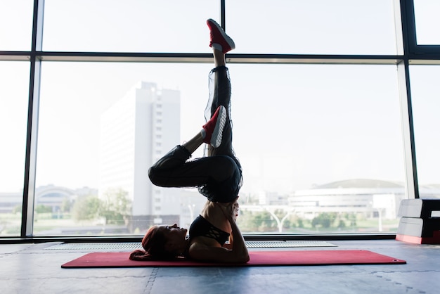 Foto de mujer fitness en colchoneta de ejercicios. Atleta femenina acostada sobre su espalda después de un entrenamiento de gimnasio