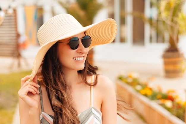 Foto de mujer hermosa joven con gafas de sol y sombrero caminando por las calles de la ciudad