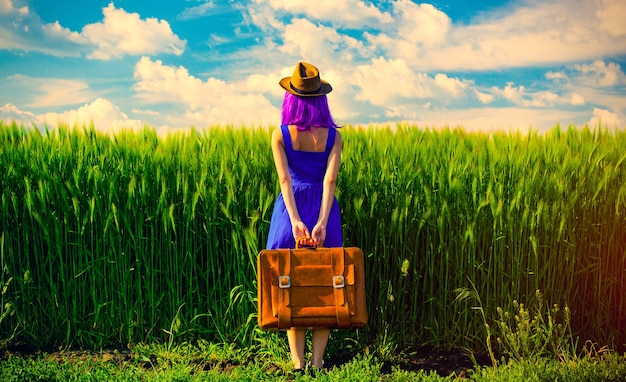 Foto de mujer hermosa joven con maleta en el campo. Concepto de temporada de horario de verano