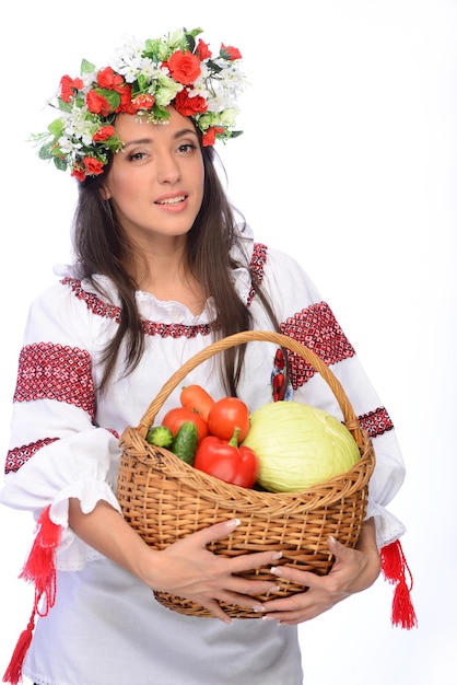 Foto de una mujer hermosa y linda en traje ucraniano con cesta de verduras