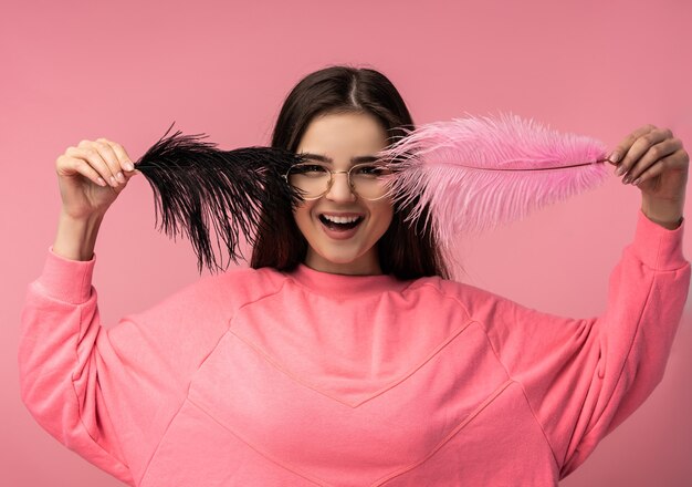 Foto foto de mujer joven atractiva con gafas cubre la cara por plumas y sonrisas