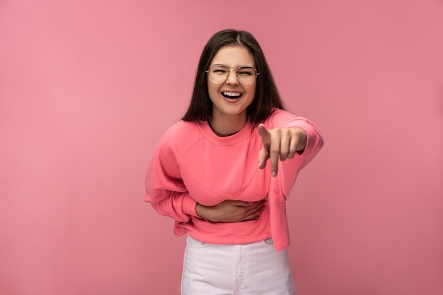 Foto de mujer joven atractiva con gafas se ríe apuntando a la cámara