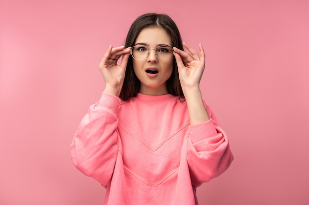 Foto de mujer joven atractiva con gafas se ve inesperadamente y sorprendida