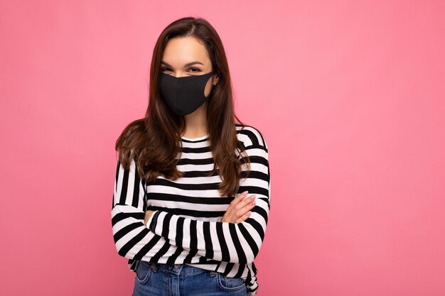 Foto de mujer joven y atractiva con mascarilla de tela de algodón hecha a mano aislada sobre pared de colores de fondo. Protección contra COVID-19