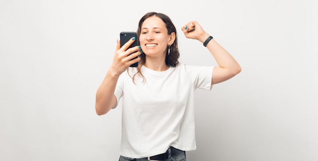 Una foto de una mujer joven emocionada mirando su teléfono ganando el juego