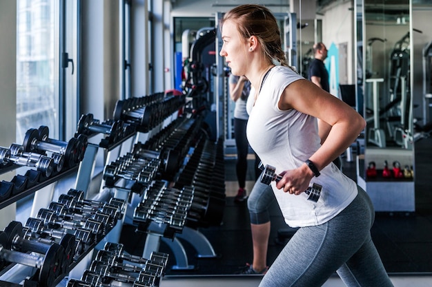 Foto de mujer joven y hermosa trabajando con pesas en el gimnasio