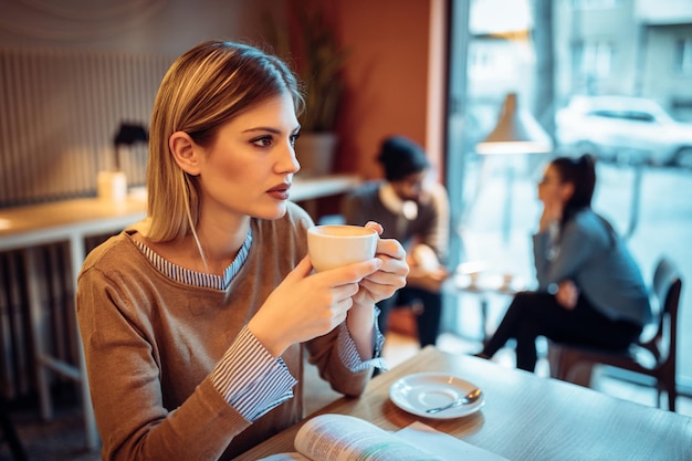 Foto de una mujer joven que estudia en una cafetería.