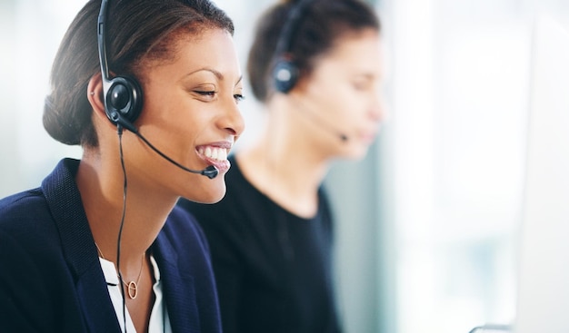 Una foto de una mujer joven que usa un auricular y una computadora en una oficina moderna