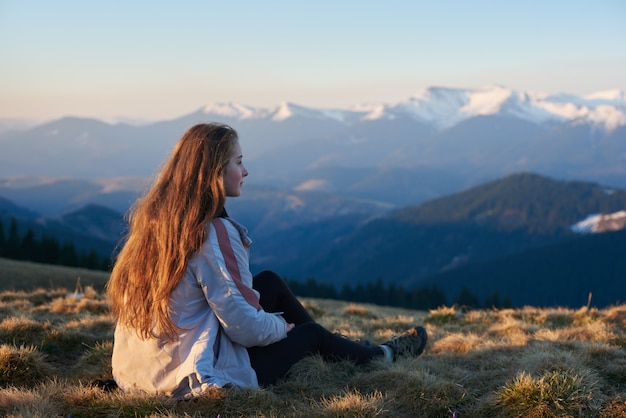 Foto de una mujer joven sentada en la cima de una montaña