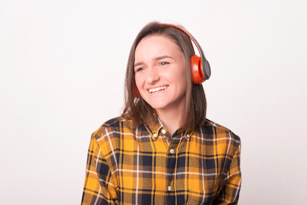 Foto de mujer joven sonriente escuchando música en auriculares y mirando a otro lado