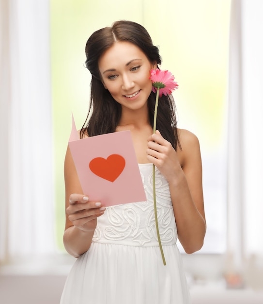 foto de mujer joven sosteniendo una flor y una postal