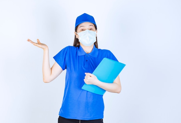 Foto de mujer joven en uniforme con máscara médica y carpeta de retención.