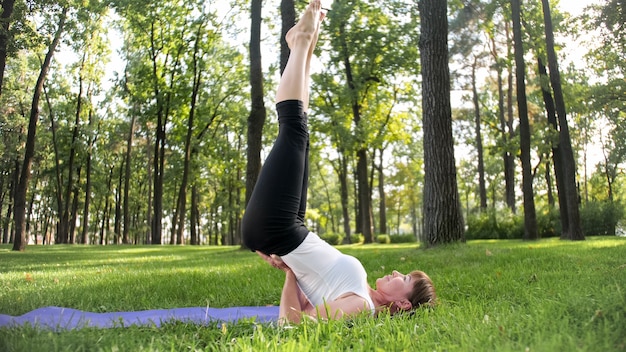 Foto de mujer de mediana edad en ropa de sportrs practicando yoga al aire libre en el parque. Mujer de mediana edad estirando y meditando en el bosque