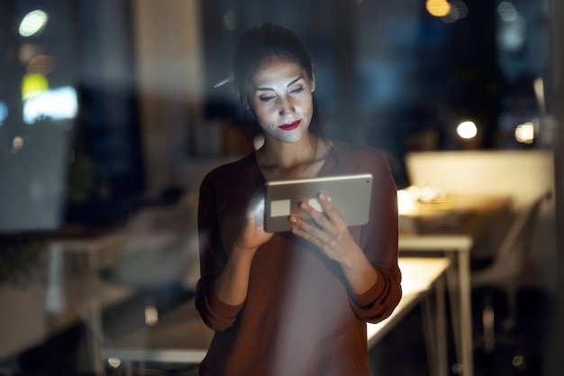 Foto de mujer de negocios bonita inteligente tomando un descanso cheking su tableta digital en la oficina.