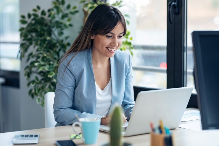 Foto foto de mujer de negocios joven y atractiva que trabaja con la computadora mientras está sentado en el escritorio en la oficina de inicio moderna.