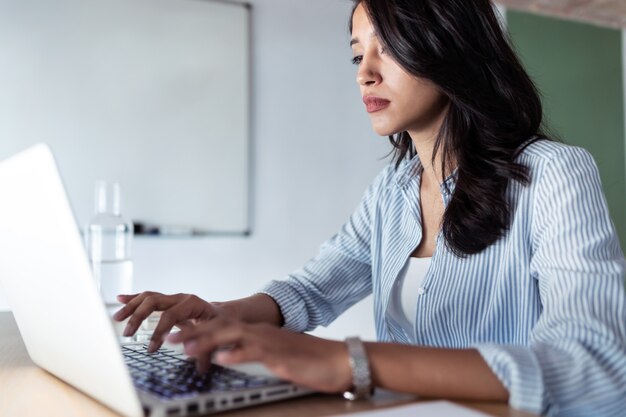 Foto de mujer de negocios joven elegante que trabaja con su computadora portátil en la oficina.