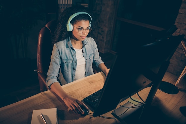 Foto de mujer de negocios mira trabajo en pantalla grande horas extras uso auriculares