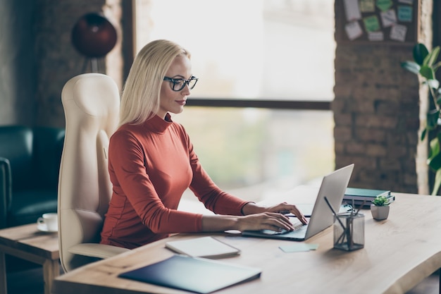 Foto de mujer reflexiva seriamente interesada navegando a través de las redes sociales en una computadora portátil en busca de datos apropiados trabajando como administrador de contenido