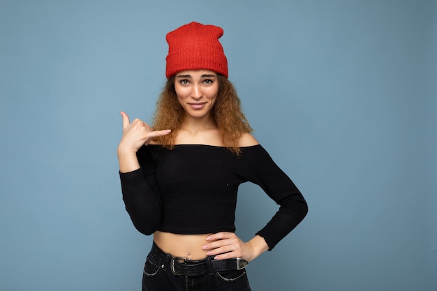 Foto de mujer rizada morena hermosa joven positiva con emociones sinceras vistiendo crop top negro