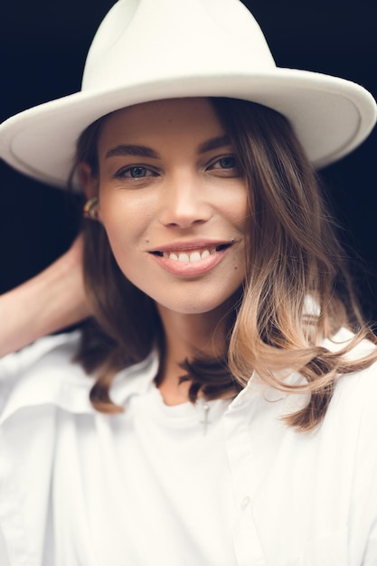 Foto de una mujer con sombrero posa en la calle contra edificios