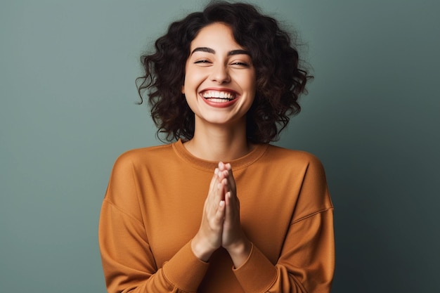 Una foto de una mujer sonriendo. Está de pie mostrando sus manos.