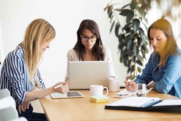 Foto de mujeres empresarias bastante jóvenes trabajando con nuevas ideas en el espacio de coworking.