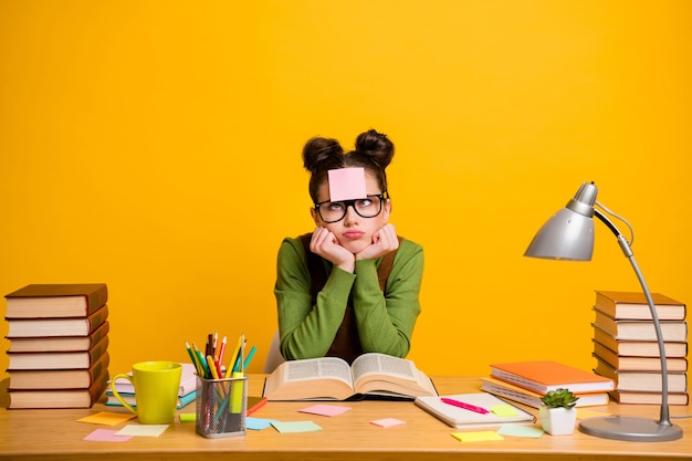 Foto de niña aburrida nerd geek aprendizaje nota adhesiva en la frente en el fondo