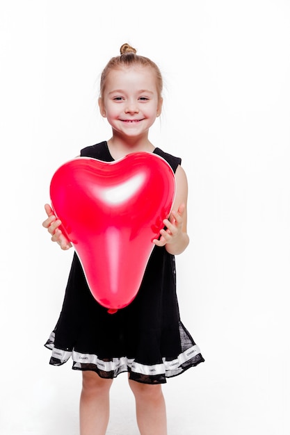 Foto de niña con un elegante vestido negro sosteniendo un globo rojo en forma de corazón