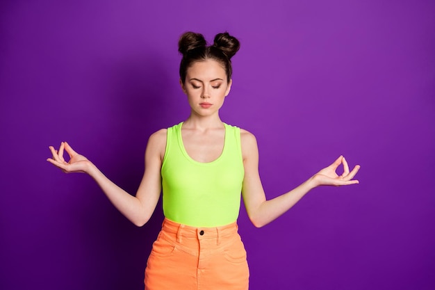 Foto de niña enfocada meditar yoga usar camiseta sin mangas aislada sobre fondo de color violeta brillante