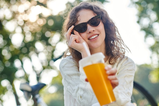Una foto de una niña con gafas de sol y una botella de agua en la mano.