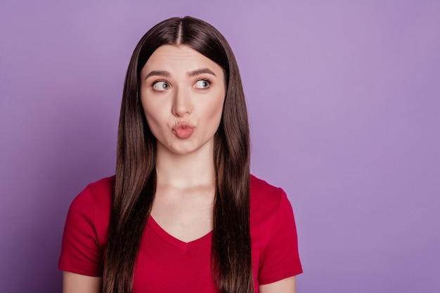 Foto de niña haciendo pucheros labios enviar aire beso sueño mirar espacio vacío aislado sobre fondo de color violeta