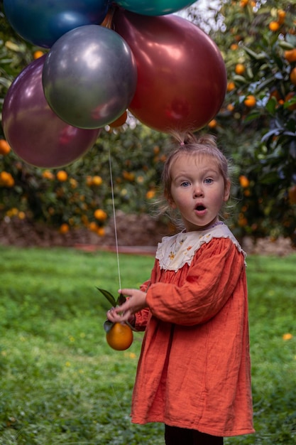 Foto de una niña en el jardín entre árboles frutales.