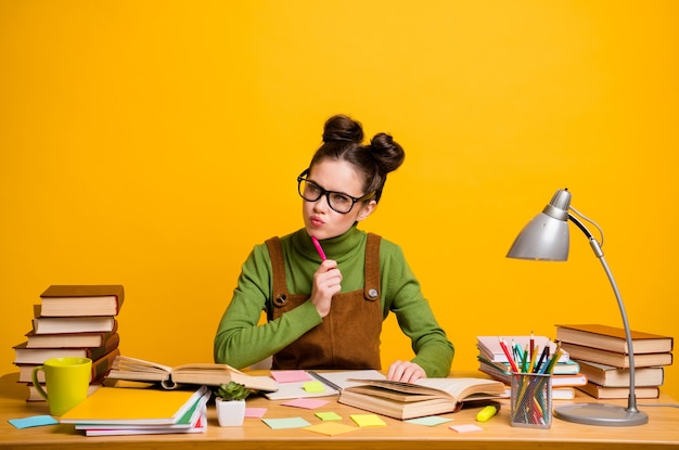 Foto de niña mentalizada sentarse mesa escribir informe creo que usar suéter aislado sobre fondo de color brillo