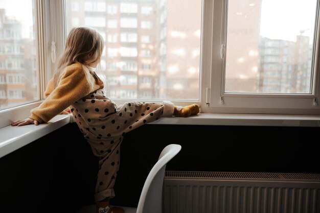 foto de una niña mirando por la ventana