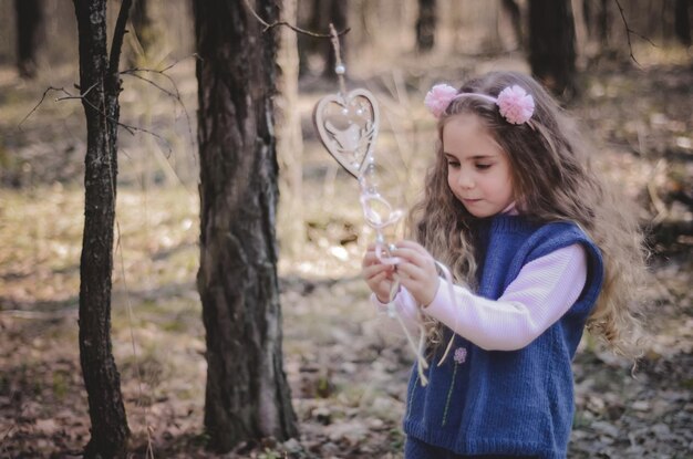 Foto de niña vestida de estilo vintage jugando en el bosque