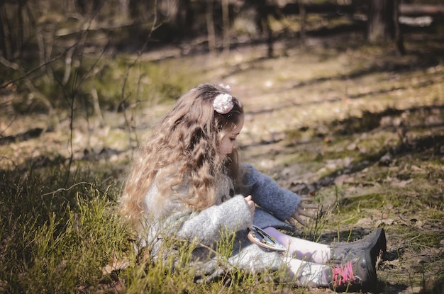 Foto de niña vestida de estilo vintage jugando en el bosque