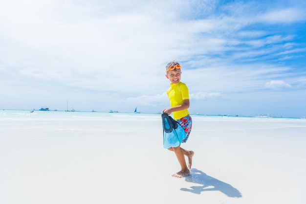 Foto de niño feliz snorkel en traje de baño amarillo en la playa blanca