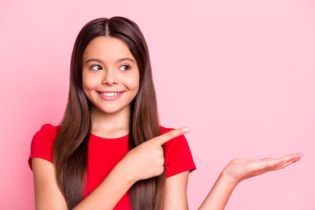 Foto de niño niña mantenga mano punto dedo índice copyspace use camiseta roja aislada sobre fondo de color pastel