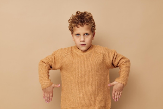 Foto foto de un niño con un suéter beige posando un estilo de vida divertido sin cambios