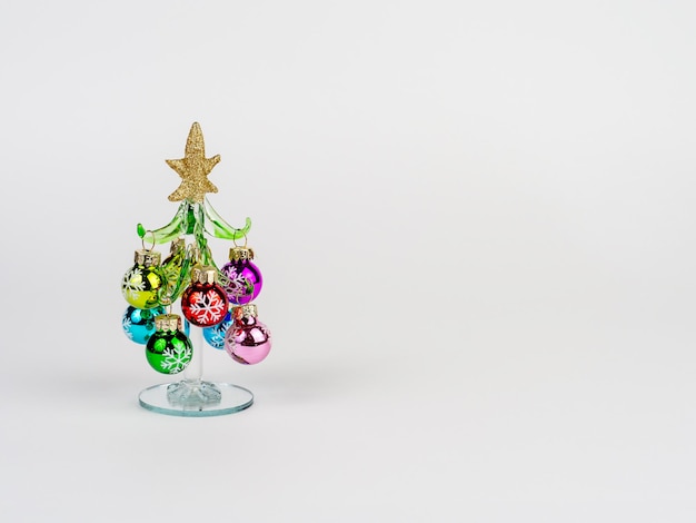 Foto de Nochevieja con un árbol de Navidad de cristal decorado con juguetes sobre un fondo blanco Hay espacio para el texto