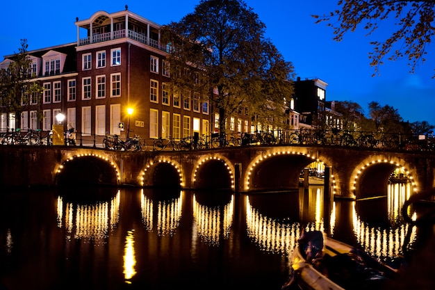 Foto noturna da cidade, muitas bicicletas na ponte do canal de amsterdã, holanda