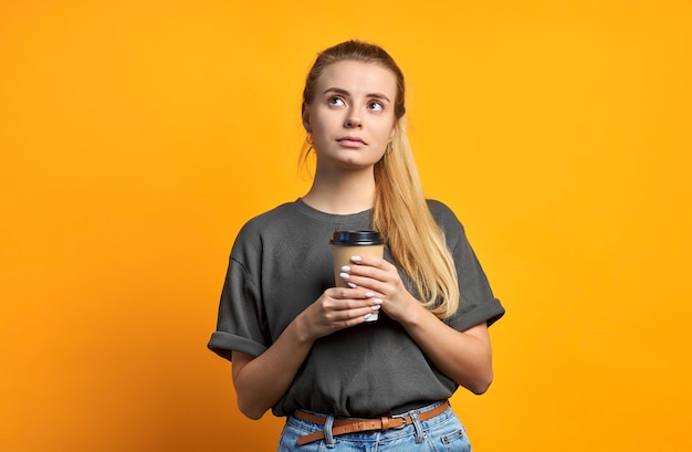 Foto de novia bastante dulce rizado positivo alegre sosteniendo una taza de café sonriendo toothily aislado sobre fondo de colores vivos