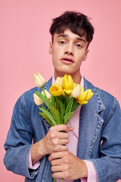 Foto de novio joven romántico en una chaqueta de mezclilla con un ramo de flores un romance de regalo Estilo de vida inalterado